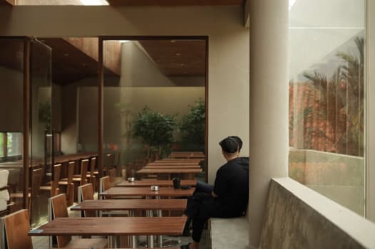 Sudut interior kafe dengan nuansa industrial dan tanaman hijau